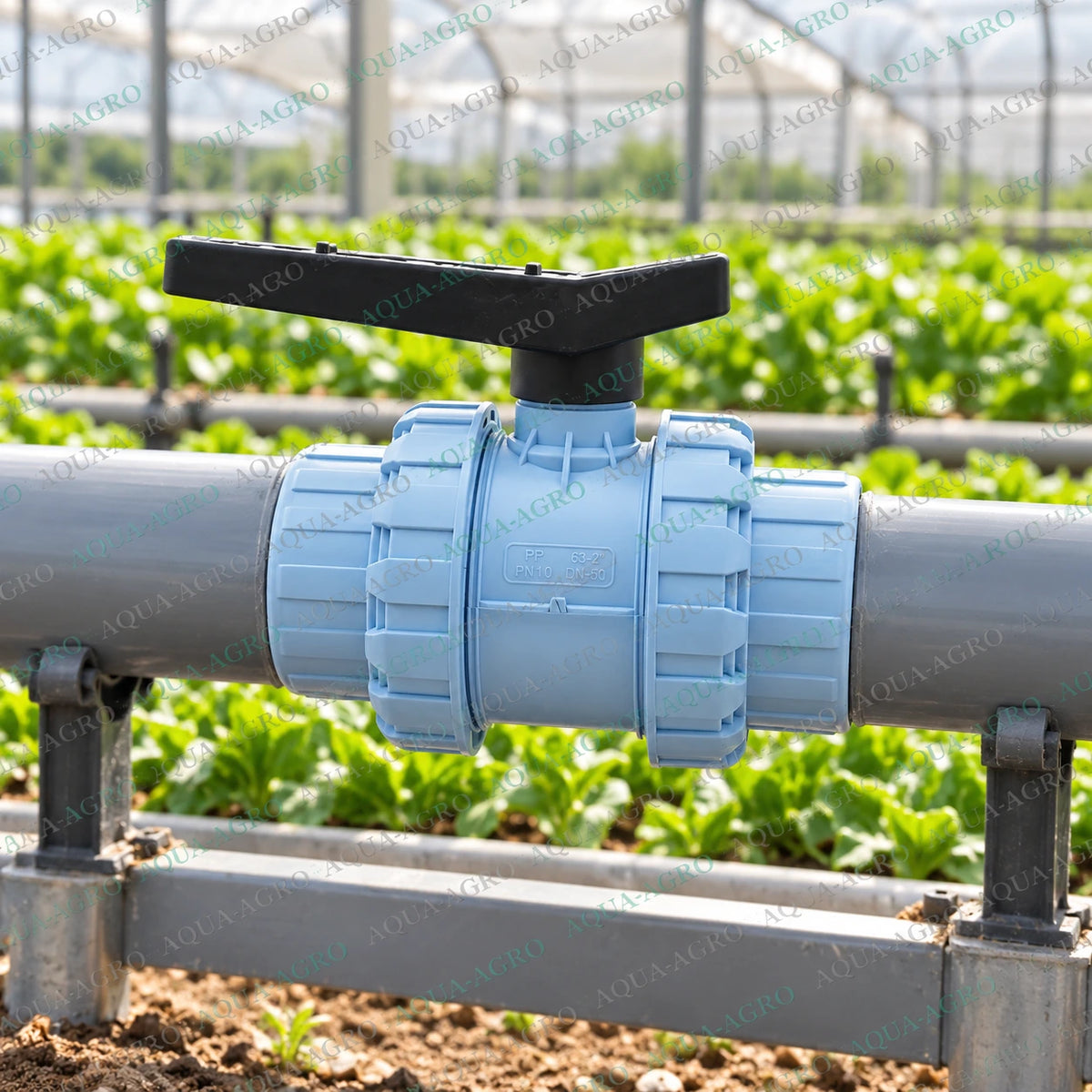 RAVANDS 2 inch PVC double union ball valve installed in agricultural greenhouse irrigation pipeline with light blue plastic body black quarter turn handle and removable union connections for water supply regulation and irrigation flow control